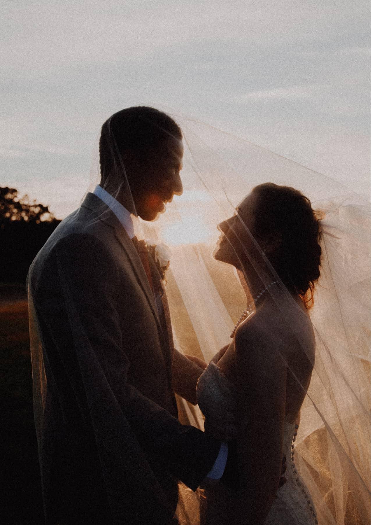 Zwei Menschen in Hochzeitskleidung die sich verliebt anschauen, fotografiert gegen die tiefstehende Herbstsonne